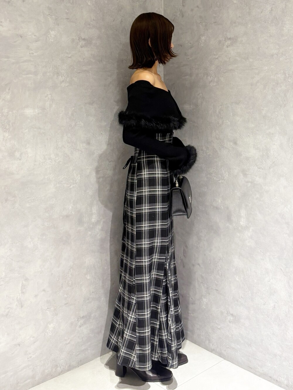 ブラック系のハンドバッグ、ブラック系のニット/セーター、ブラック系のスカートを着用したレディースの秋コーディネートの3枚目の写真