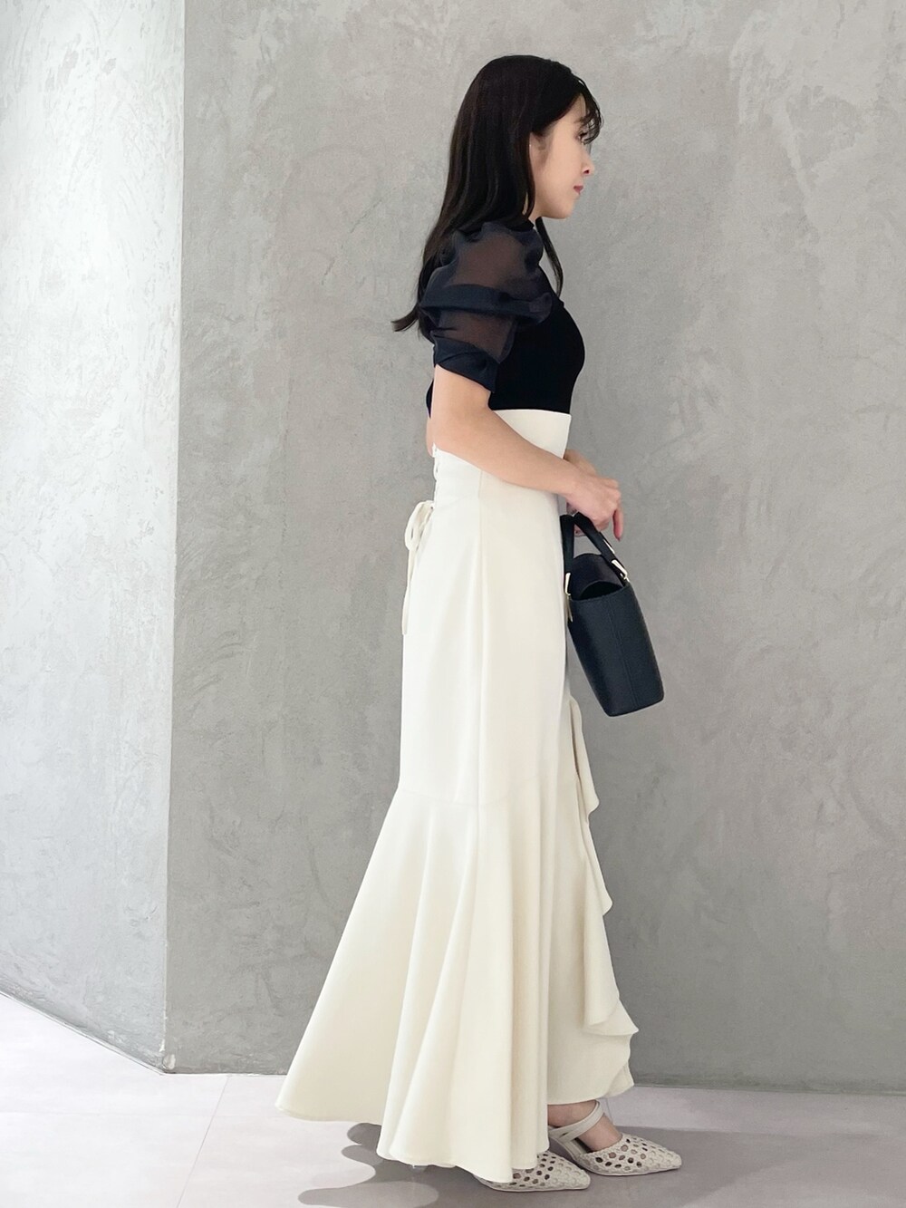 ホワイト系のパンプス、ブラック系のハンドバッグ、ブラック系のニット/セーターを着用したレディースの春コーディネートの2枚目の写真