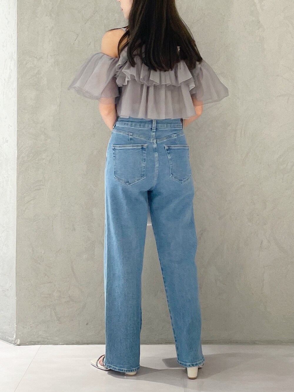 ブルー系のデニムパンツ、ホワイト系のサンダル、ホワイト系のトートバッグを着用したレディースの夏コーディネートの4枚目の写真