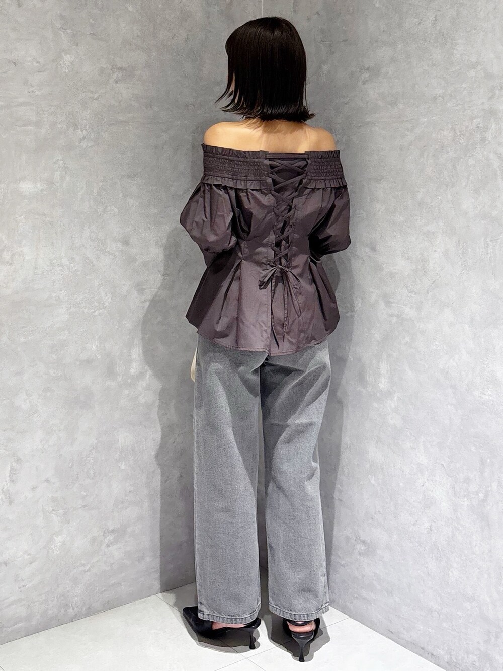 ホワイト系のハンドバッグ、ブラック系のパンプス、グレー系のデニムパンツを着用したレディースの夏コーディネートの4枚目の写真