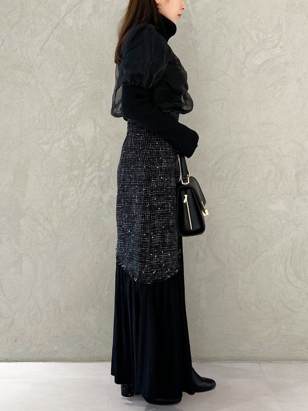 ブラック系のスカート、ブラック系のショルダーバッグ、ブラック系のブーツを着用したレディースの秋コーディネートの8枚目の写真