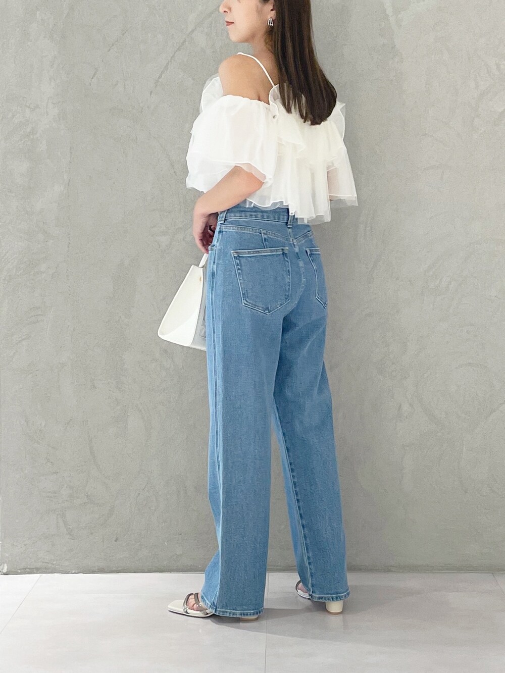 ブルー系のデニムパンツ、ホワイト系のショルダーバッグ、ホワイト系のサンダルを着用したレディースの夏コーディネートの3枚目の写真