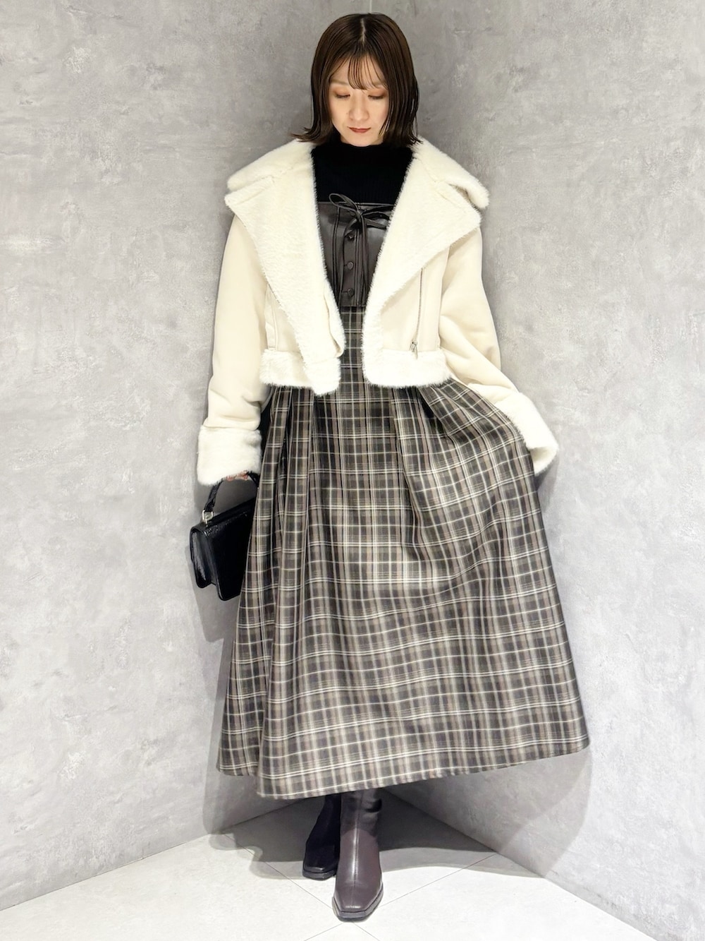 ブラック系のニット/セーター、ホワイト系のムートンコート、ブラック系のハンドバッグを着用したレディースの冬コーディネートの5枚目の写真