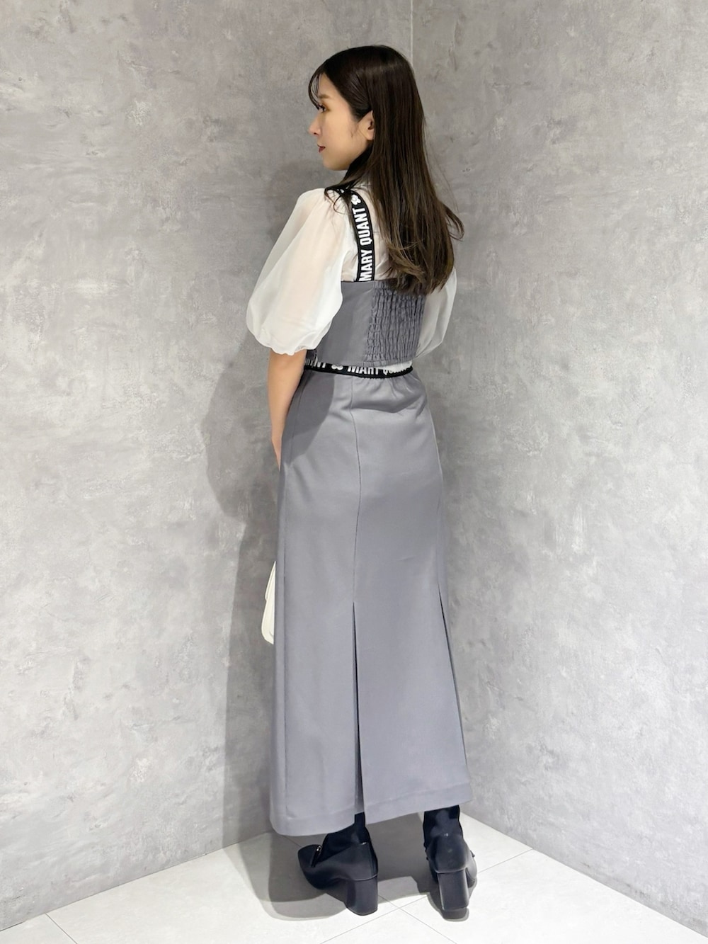 グレー系のスカート、ブラック系のブーツ、ホワイト系のハンドバッグを着用したレディースの春コーディネートの3枚目の写真