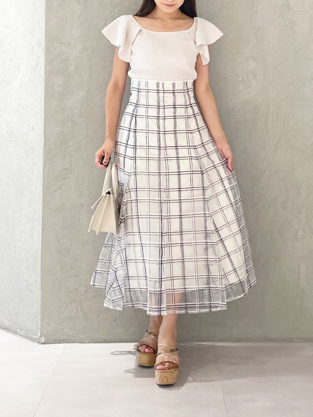 ホワイト系のスカート、ブラウン系のサンダル、ベージュ系のショルダーバッグを着用したレディースの夏コーディネートの6枚目の写真