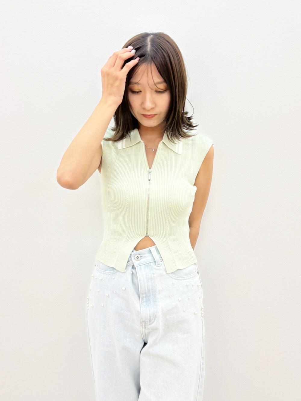 ブルー系のデニムパンツ、グリーン系のニット/セーターを着用したレディースの夏コーディネートの2枚目の写真