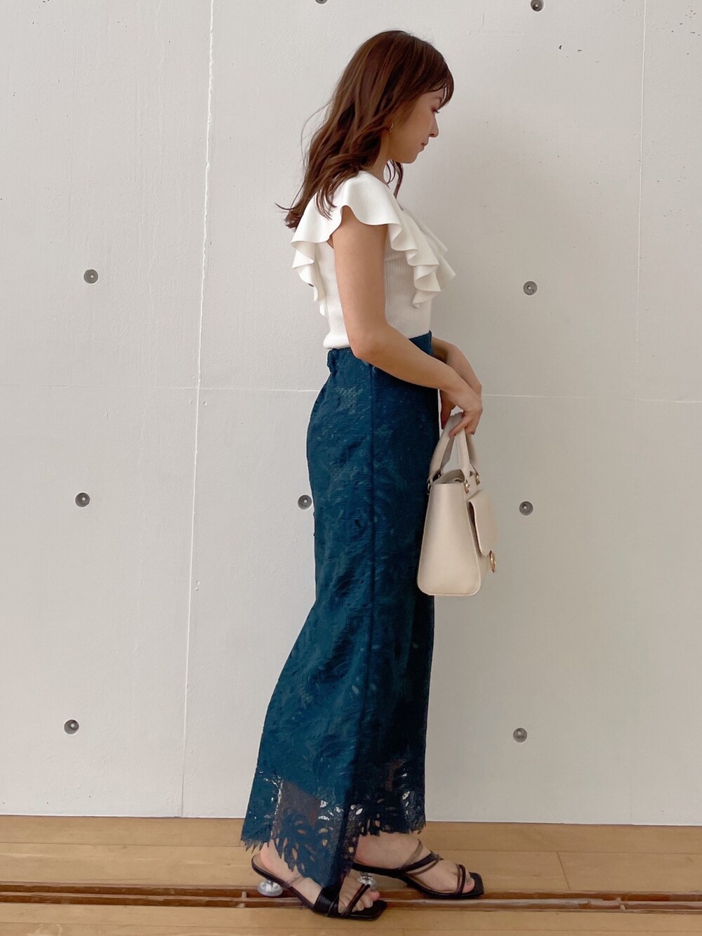 グリーン系のスカート、ブラック系のサンダル、ホワイト系のハンドバッグを着用したレディースの春コーディネートの3枚目の写真