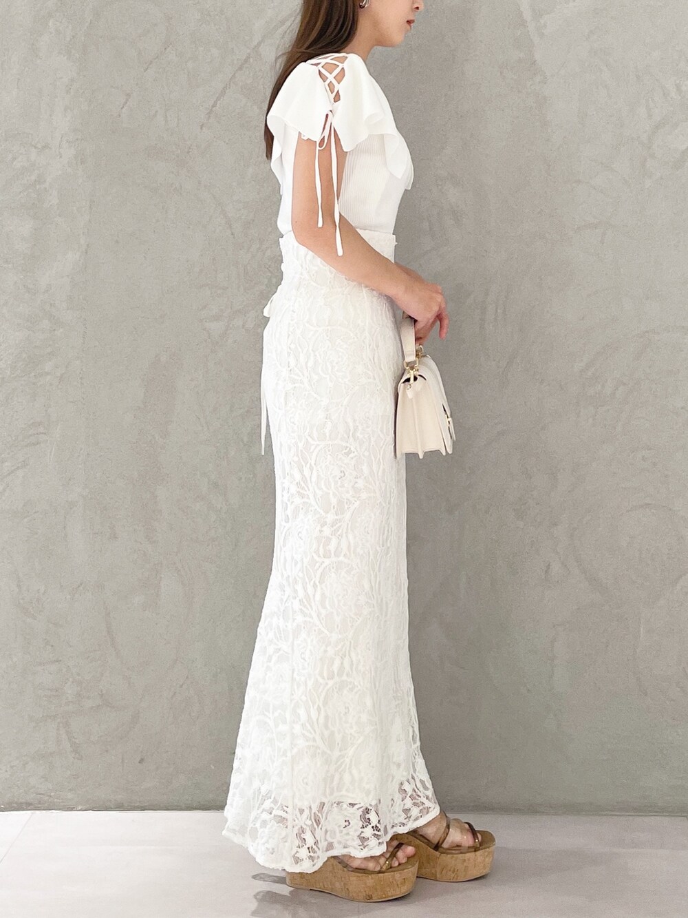 ホワイト系のハンドバッグ、ホワイト系のニット/セーター、ホワイト系のスカートを着用したレディースの春コーディネートの2枚目の写真