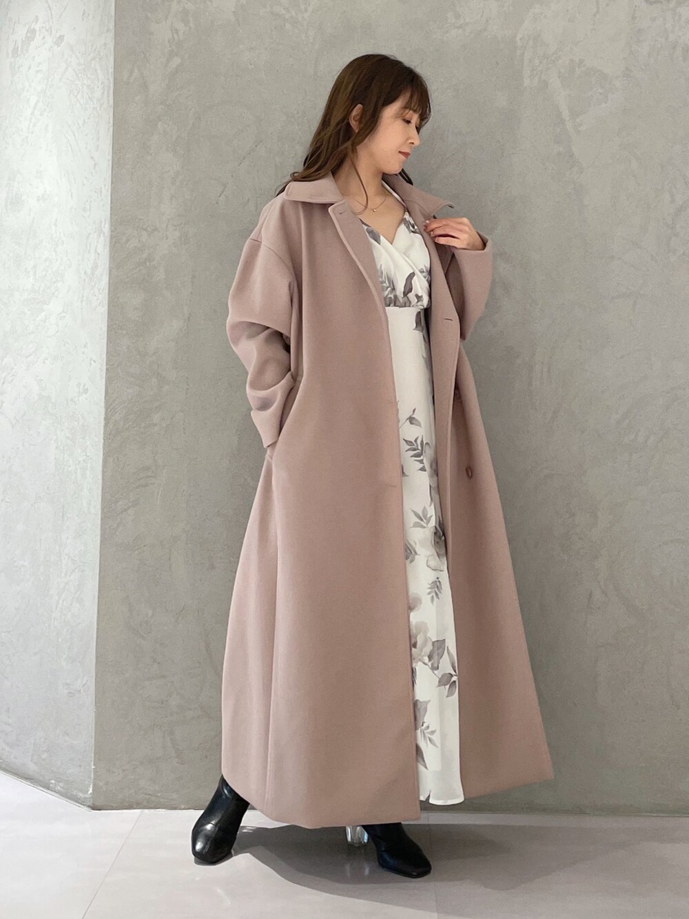 ホワイト系のワンピース、ベージュ系のステンカラーコート、ブラック系のブーツを着用したレディースの冬コーディネートの2枚目の写真