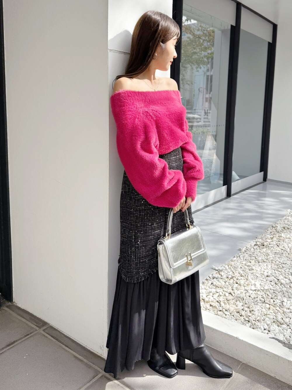 ブラック系のスカート、ブラック系のブーツ、シルバー系のハンドバッグを着用したレディースの秋コーディネートの3枚目の写真