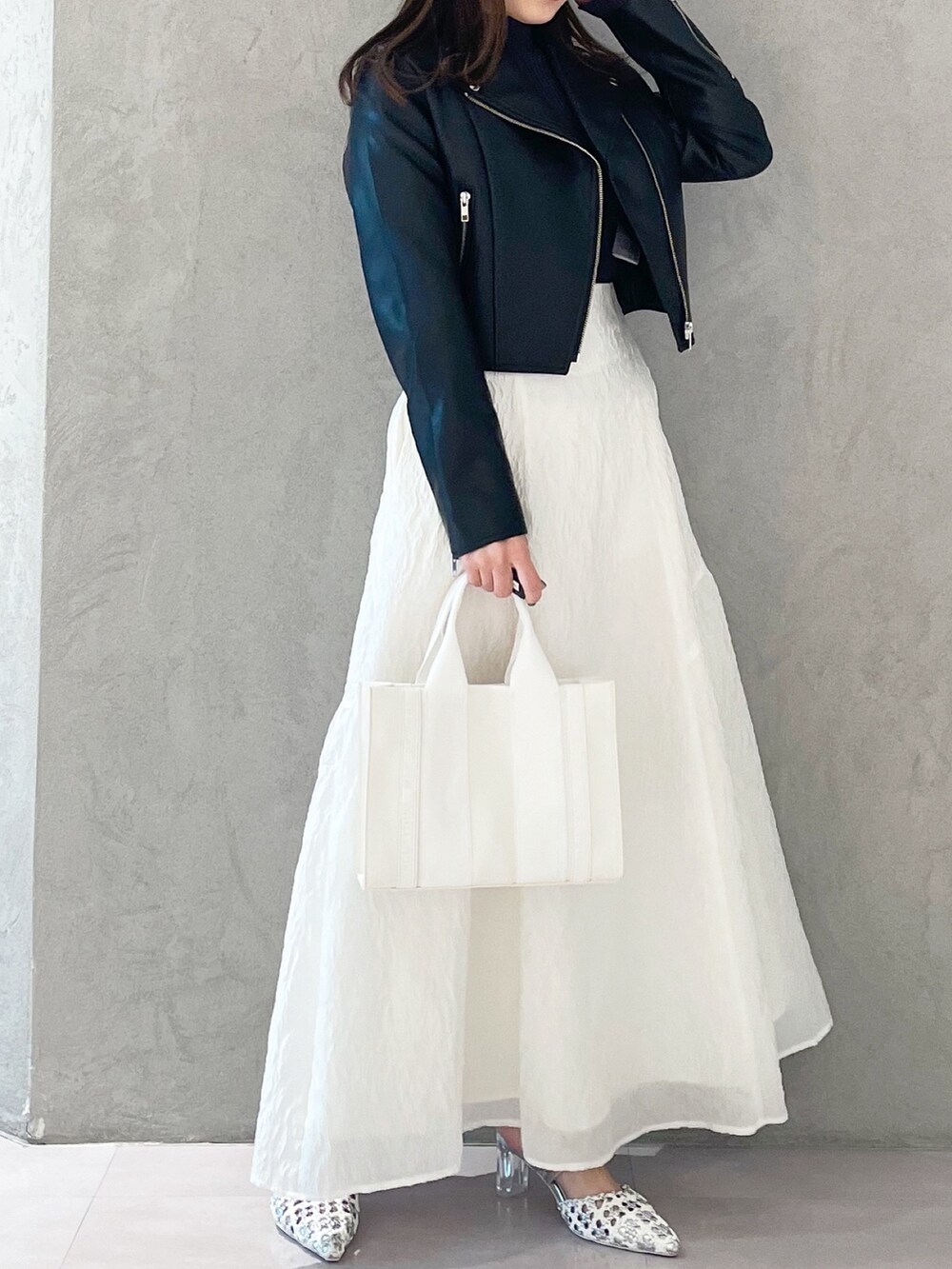 シルバー系のパンプス、ホワイト系のトートバッグ、ブラック系のライダースジャケットを着用したレディースの春コーディネートの2枚目の写真