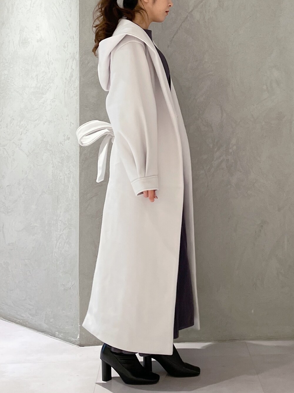 ホワイト系のチェスターコート、ブラック系のブーツ、ブルー系のワンピースを着用したレディースの秋コーディネートの2枚目の写真