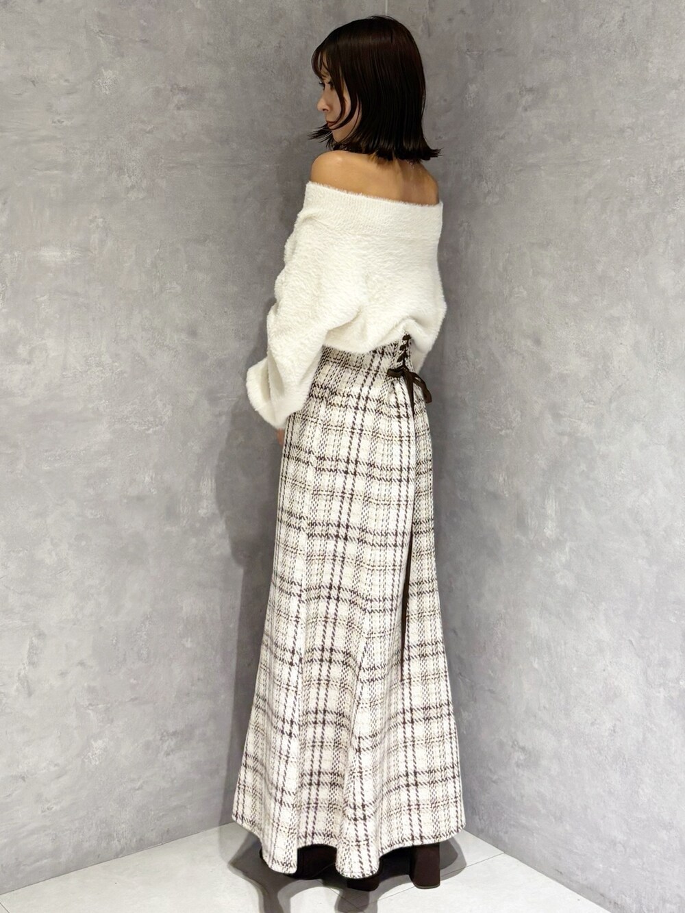 ホワイト系のスカート、ホワイト系のニット/セーター、ブラウン系のブーツを着用したレディースの秋コーディネートの3枚目の写真