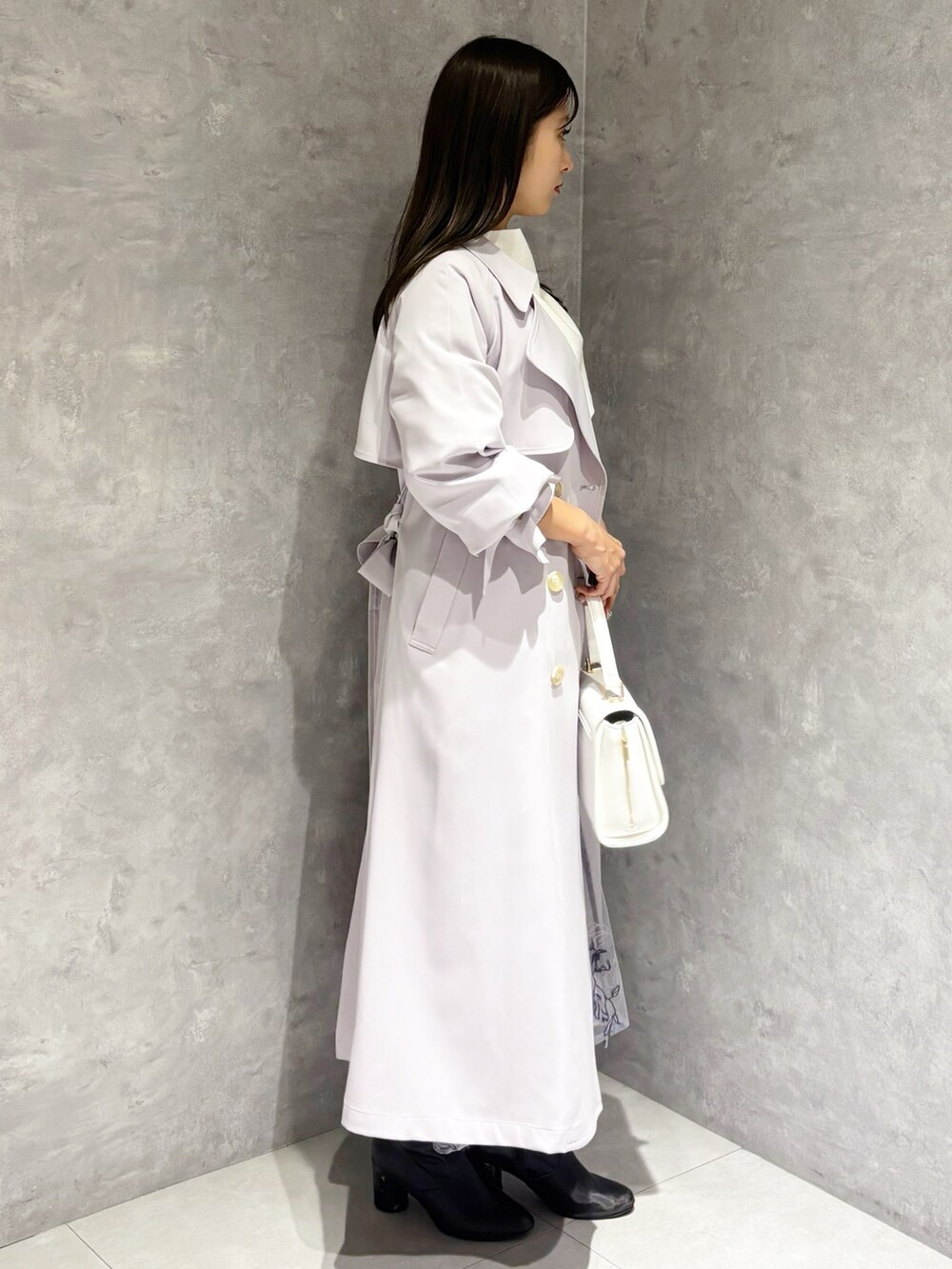 パープル系のスカート、ブラック系のブーツ、ホワイト系のハンドバッグを着用したレディースの冬コーディネートの2枚目の写真