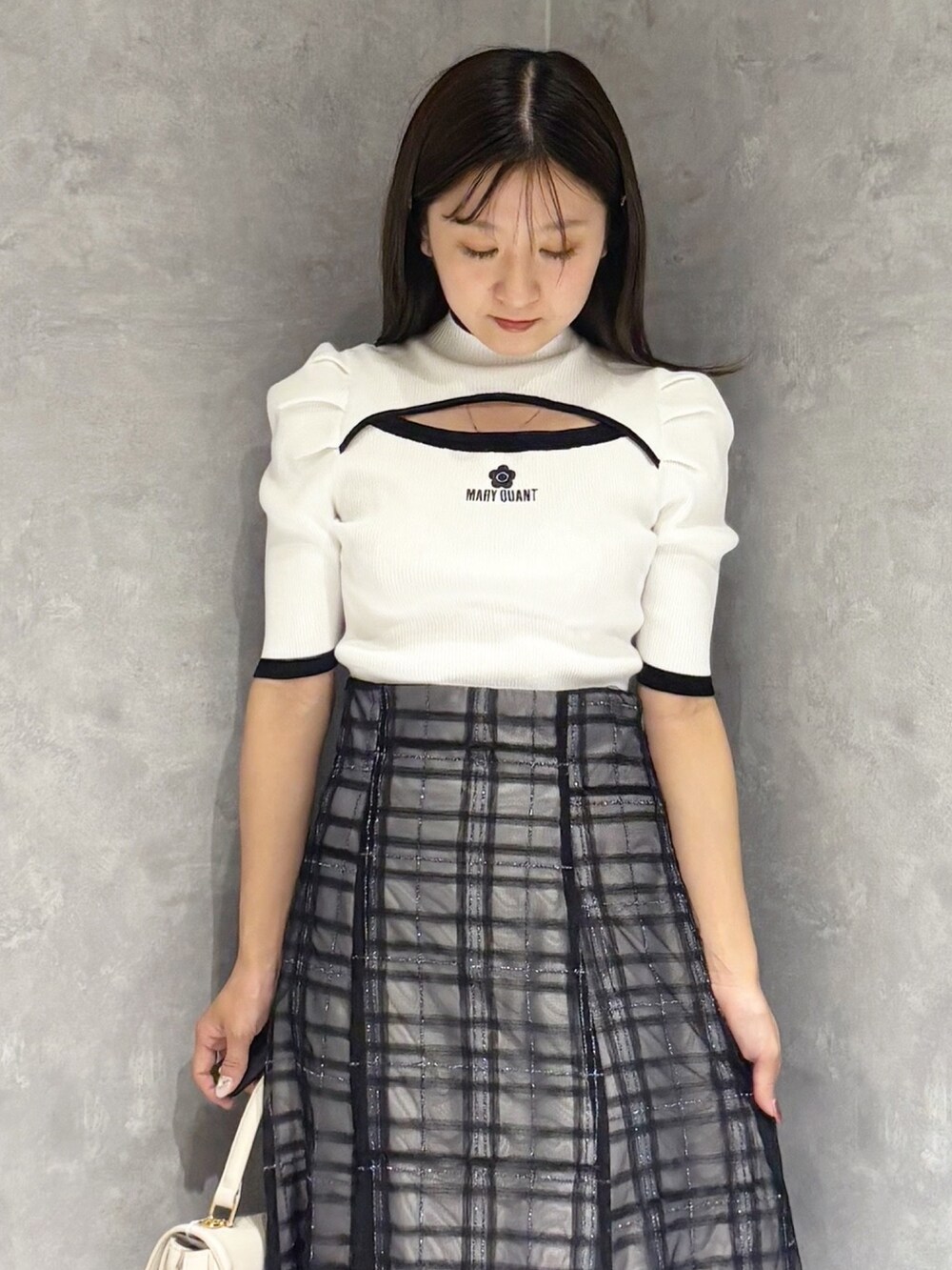 ブルー系のスカート、ブラック系のパンプス、ホワイト系のハンドバッグを着用したレディースの春コーディネートの5枚目の写真