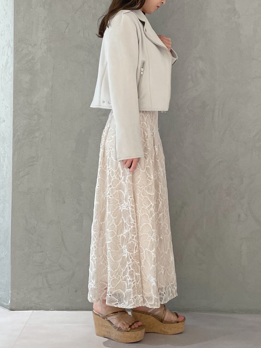 ブラウン系のサンダル、ホワイト系のニット/セーター、ホワイト系のライダースジャケットを着用したレディースの春コーディネートの6枚目の写真