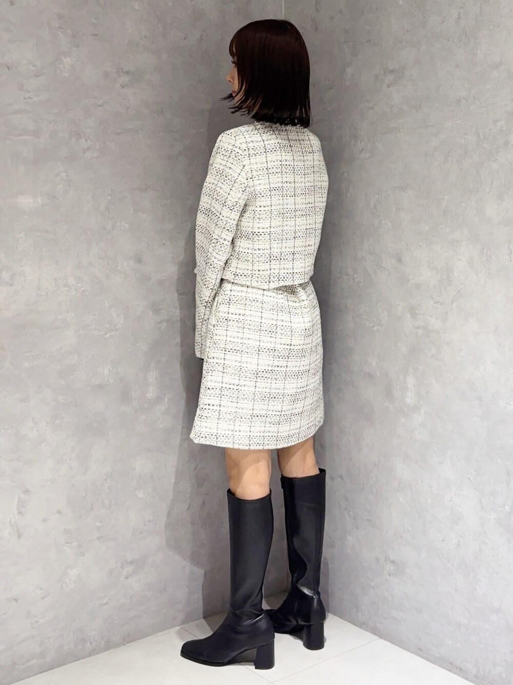 ホワイト系のスカート、ブラック系のブーツ、ブラック系のハンドバッグを着用したレディースの秋コーディネートの5枚目の写真