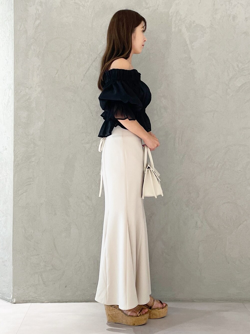 ホワイト系のスカート、ブラウン系のサンダル、ベージュ系のショルダーバッグを着用したレディースの夏コーディネートの3枚目の写真