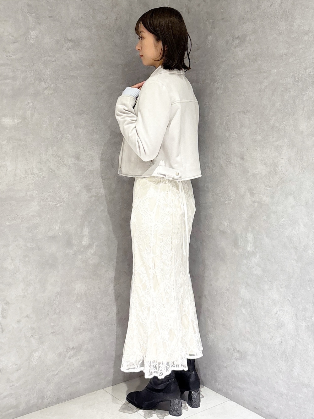 ホワイト系のスカート、ブルー系のニット/セーター、ベージュ系のライダースジャケットを着用したレディースの冬コーディネートの3枚目の写真