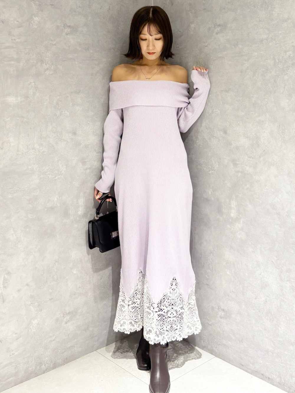 パープル系のワンピース、ブラック系のハンドバッグ、ブラウン系のブーツを着用したレディースの秋コーディネートの6枚目の写真