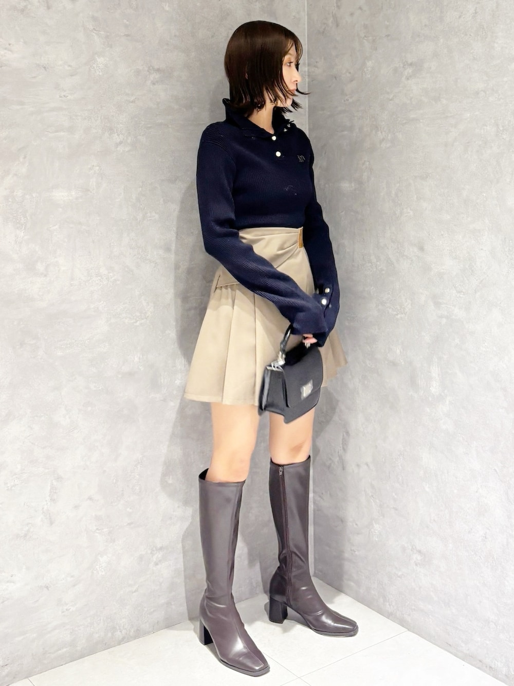 ベージュ系のスカート、ブラウン系のブーツ、ブラック系のハンドバッグを着用したレディースの冬コーディネートの3枚目の写真