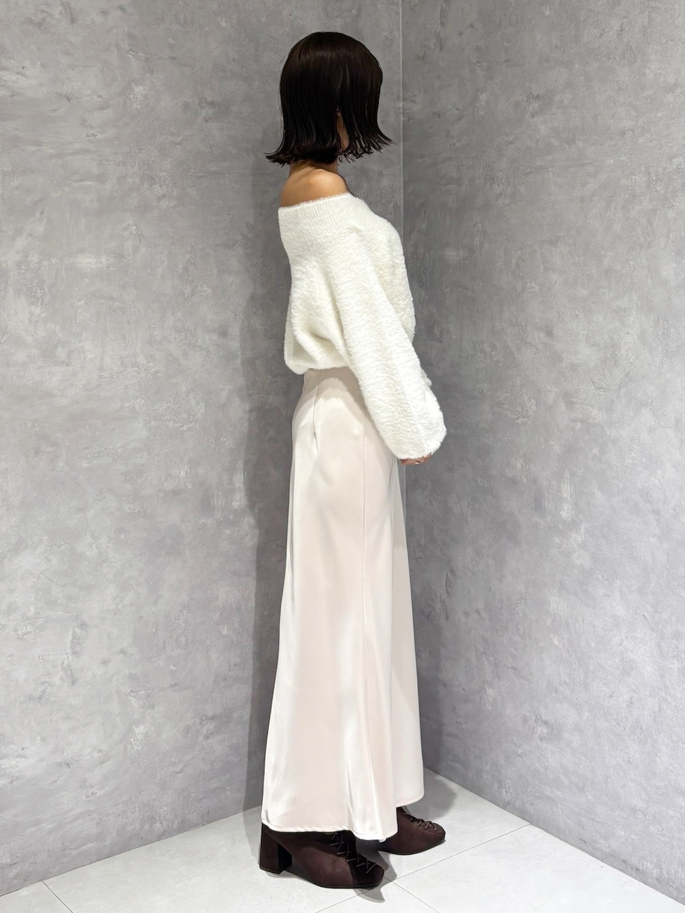 ピンク系のスカート、ホワイト系のニット/セーター、ブラウン系のブーツを着用したレディースの秋コーディネートの2枚目の写真