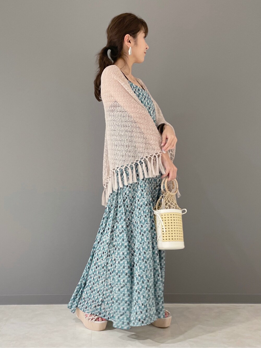 グリーン系のワンピース、ホワイト系のハンドバッグ、ホワイト系のサンダルを着用したレディースの春コーディネートの3枚目の写真