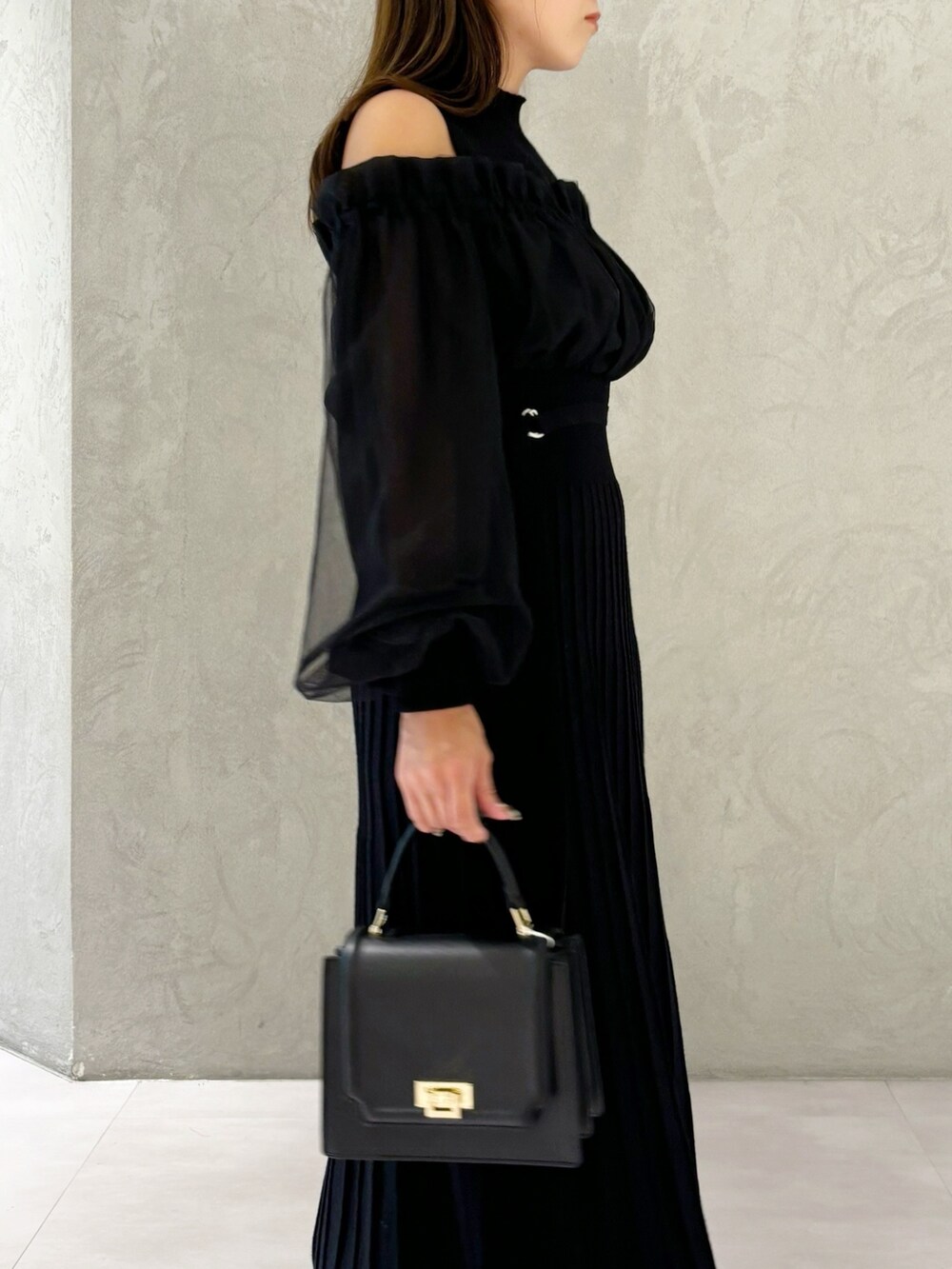 ブラック系のワンピース、ブラック系のブーツ、ブラック系のハンドバッグを着用したレディースの秋コーディネートの7枚目の写真