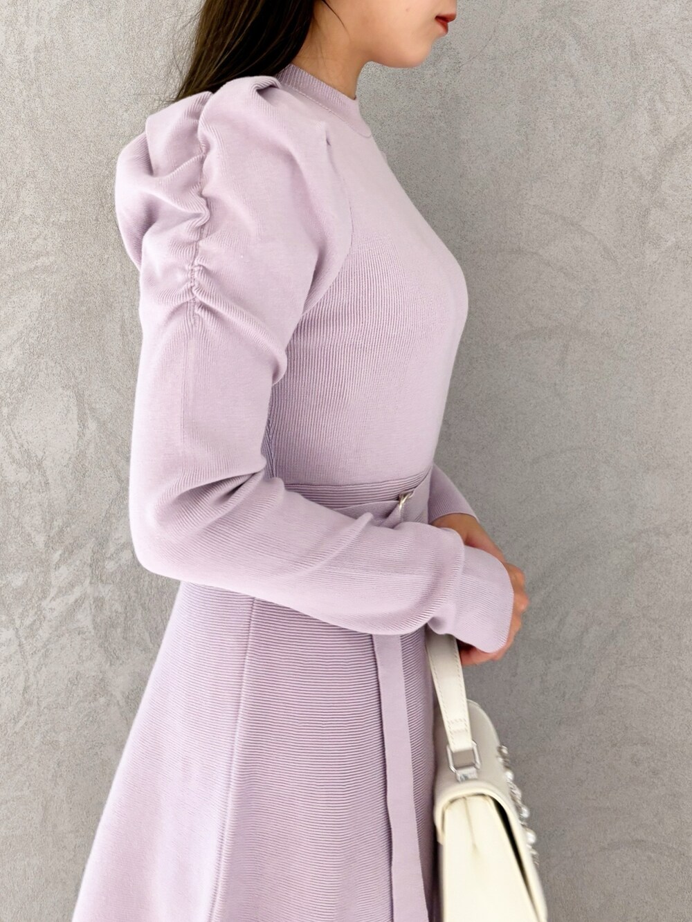 ホワイト系のショルダーバッグ、ブラック系のブーツ、パープル系のワンピースを着用したレディースの冬コーディネートの4枚目の写真