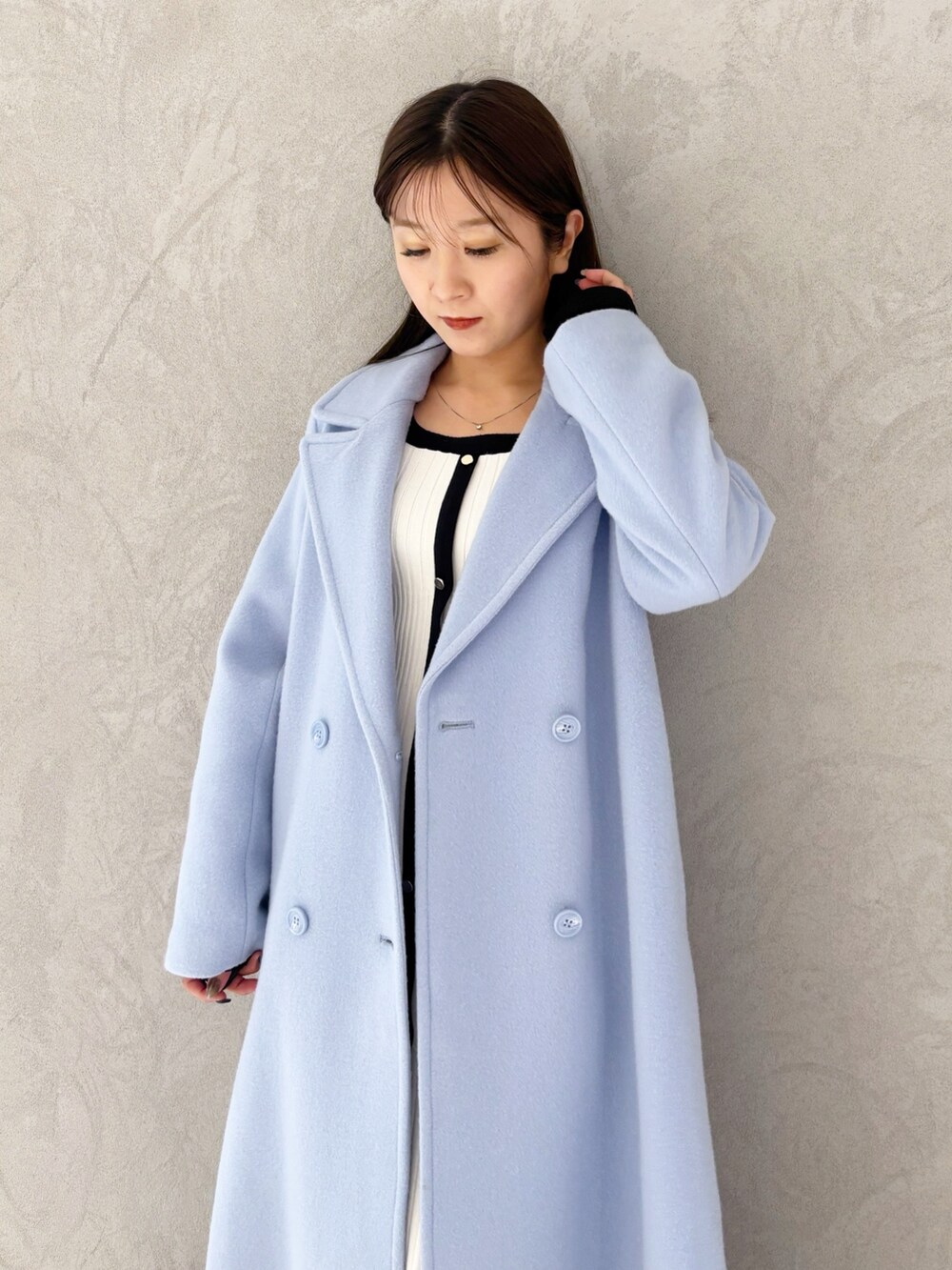 ブルー系のチェスターコート、ブラック系のブーツ、ホワイト系のワンピースを着用したレディースの冬コーディネートの8枚目の写真