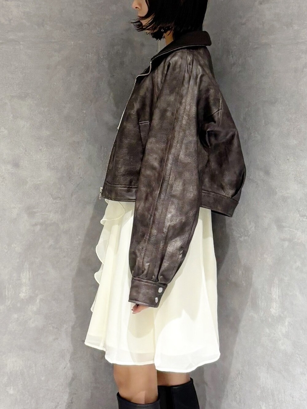 ブラック系のブーツ、ブラウン系のブルゾン、ホワイト系のワンピースを着用したレディースの秋コーディネートの4枚目の写真