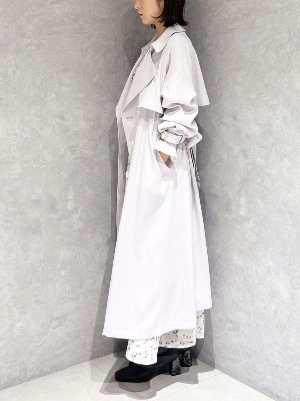 ホワイト系のワンピース、ブラック系のブーツ、パープル系のトレンチコートを着用したレディースの冬コーディネートの4枚目の写真