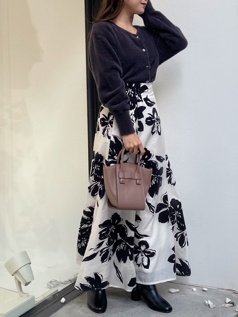 ブラウン系のハンドバッグ、ブラック系のブーツ、ホワイト系のスカートを着用したレディースの秋コーディネートの4枚目の写真