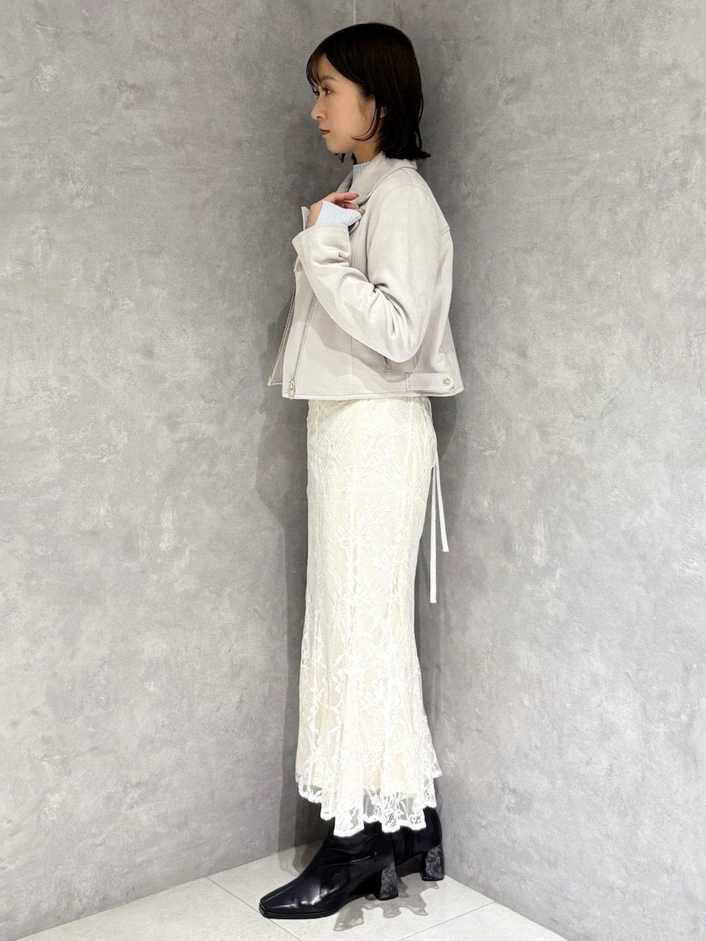 ホワイト系のスカート、ブルー系のニット/セーター、ベージュ系のライダースジャケットを着用したレディースの冬コーディネートの4枚目の写真