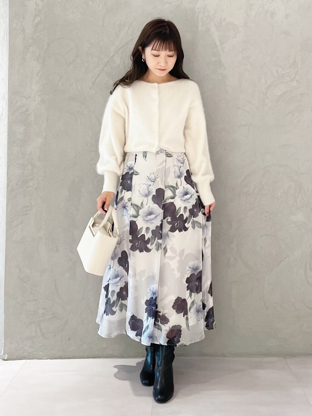 ホワイト系のハンドバッグ、ブラック系のブーツ、ブルー系のスカートを着用したレディースの秋コーディネートの5枚目の写真