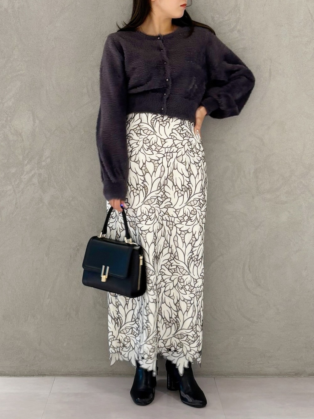 ホワイト系のスカート、ブラック系のブーツ、ブラック系のショルダーバッグを着用したレディースの冬コーディネートの6枚目の写真