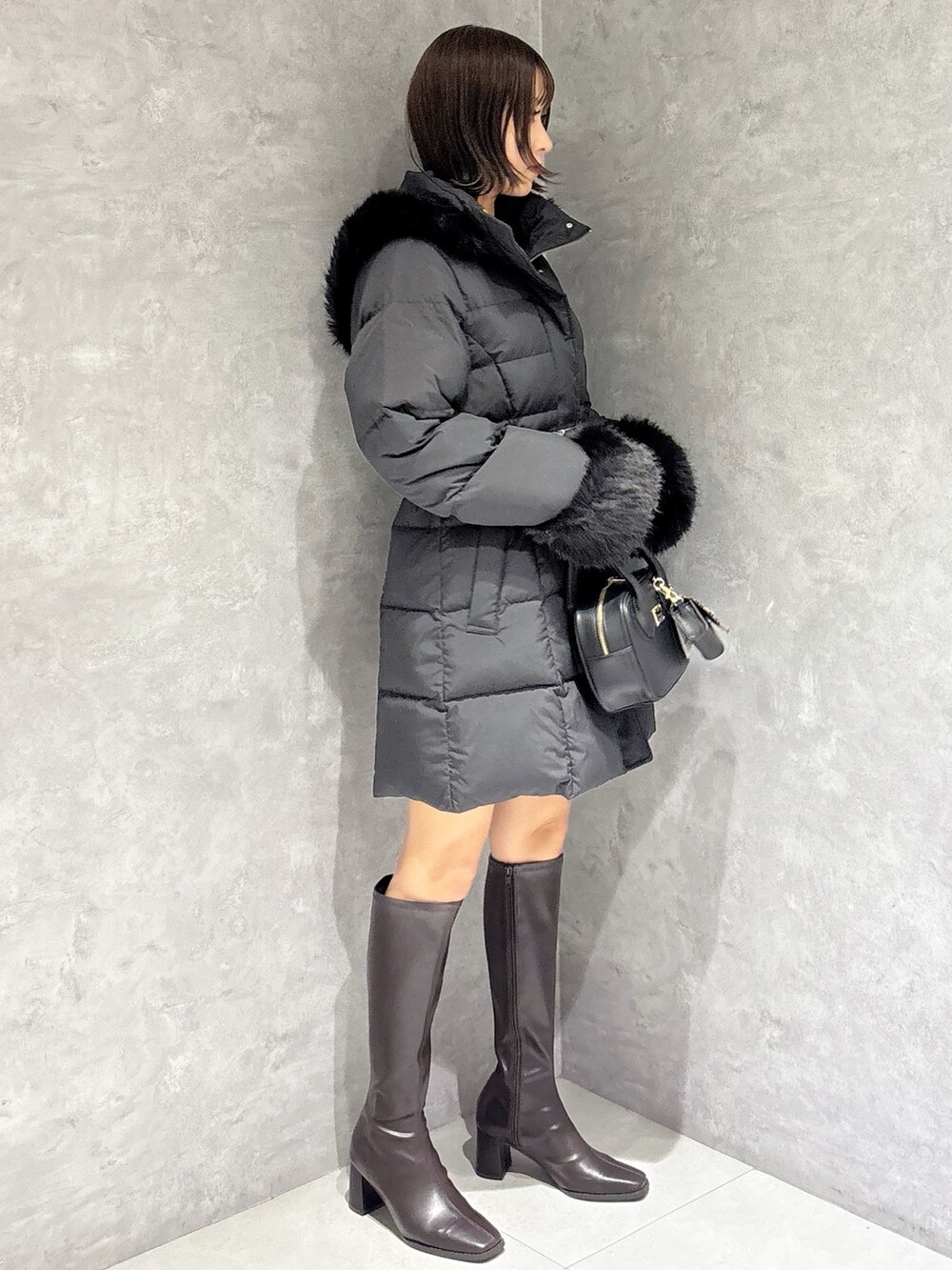 ブラウン系のブーツ、ブラック系のハンドバッグ、ブラック系のニット/セーターを着用したレディースの秋コーディネートの5枚目の写真