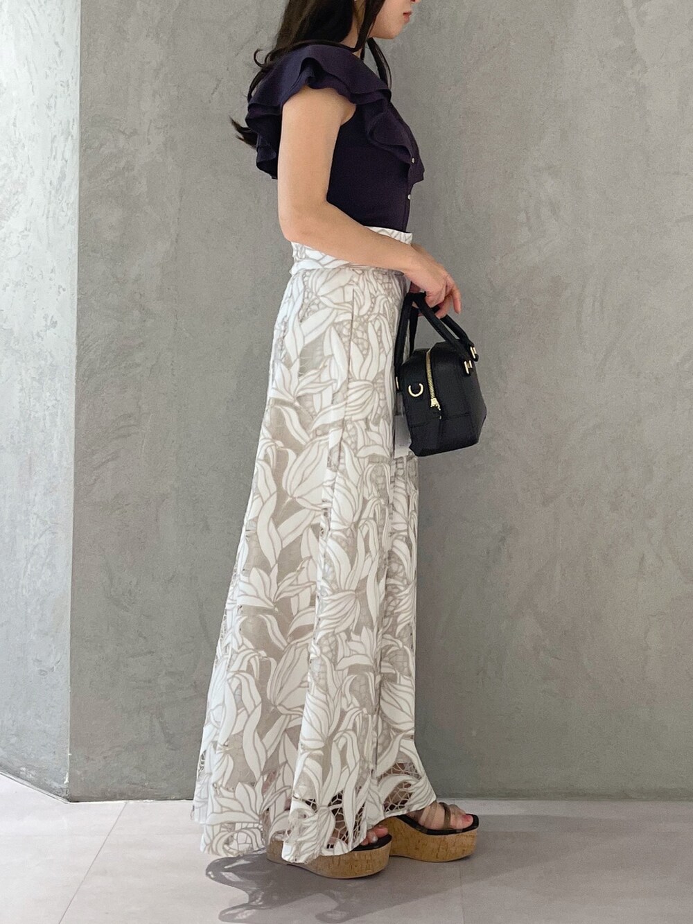 ブラック系のサンダル、ブラック系のボストンバッグ、ホワイト系のスカートを着用したレディースの春コーディネートの3枚目の写真