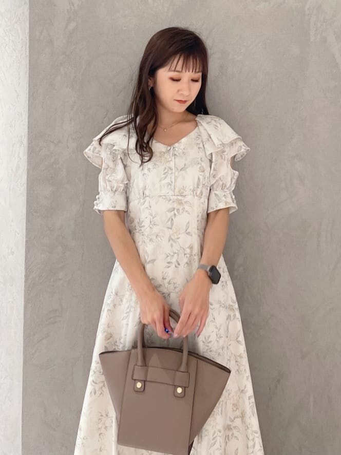 イエロー系のワンピース、ブラック系のサンダル、ブラウン系のハンドバッグを着用したレディースの夏コーディネートの2枚目の写真