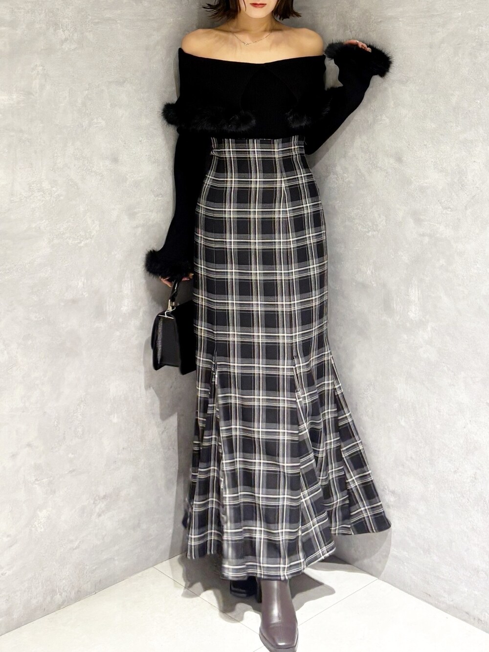 ブラック系のハンドバッグ、ブラック系のニット/セーター、ブラック系のスカートを着用したレディースの秋コーディネートの4枚目の写真