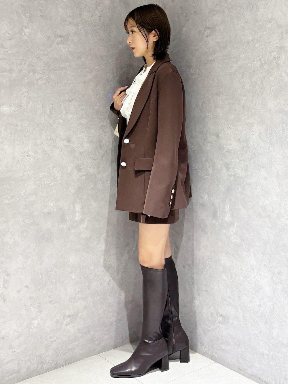 ホワイト系のシャツ/ブラウス、ホワイト系のハンドバッグ、ブラウン系のブーツを着用したレディースの春コーディネートの2枚目の写真