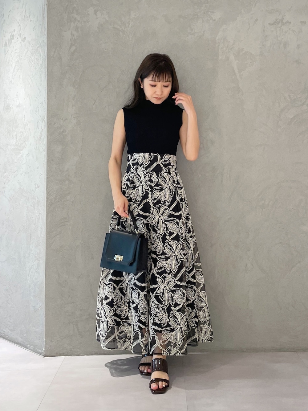 ブラウン系のサンダル、ブラック系のハンドバッグ、ブラック系のニット/セーターを着用したレディースの夏コーディネートの6枚目の写真