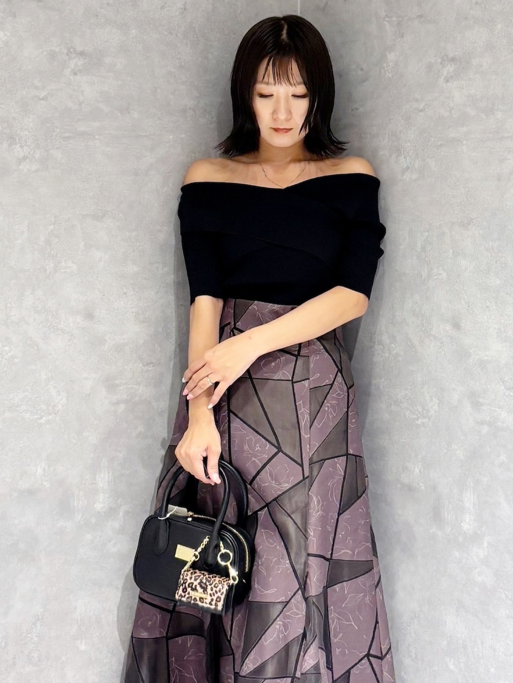 ブラウン系のスカート、ブラック系のハンドバッグ、ブラック系のニット/セーターを着用したレディースの夏コーディネートの5枚目の写真