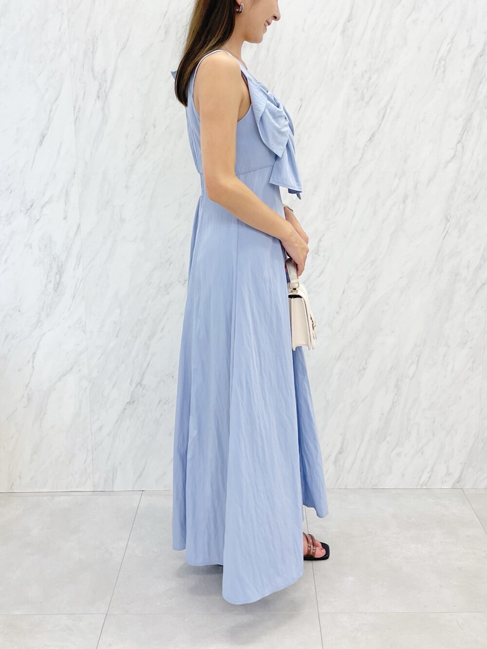 ブルー系のワンピース、ブラック系のサンダル、ホワイト系のハンドバッグを着用したレディースの夏コーディネートの2枚目の写真