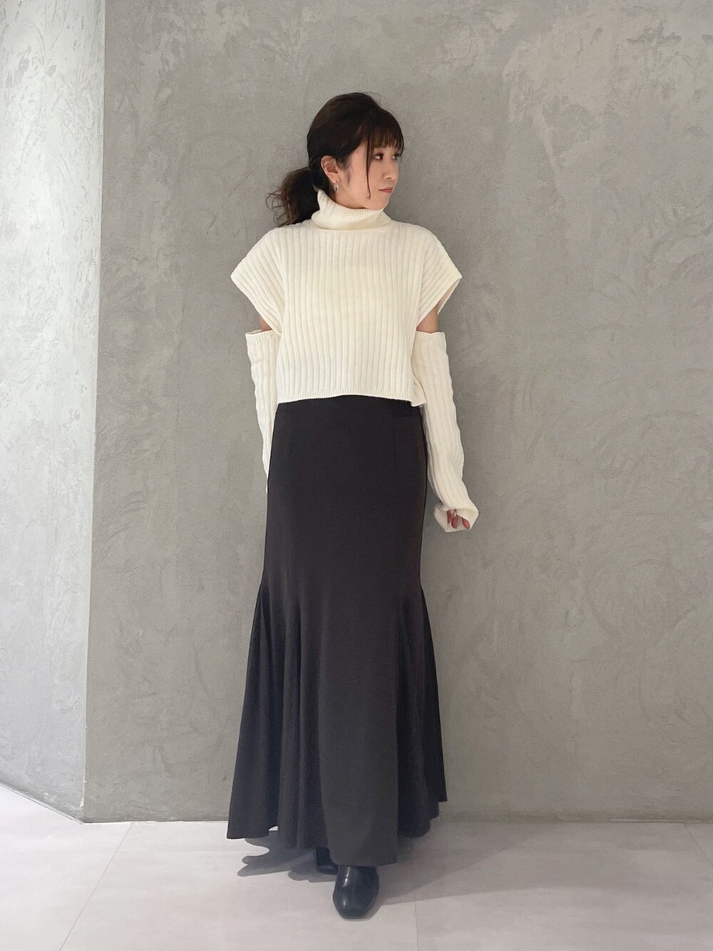 ブラウン系のスカート、ホワイト系のニット/セーターを着用したレディースの冬コーディネートの5枚目の写真