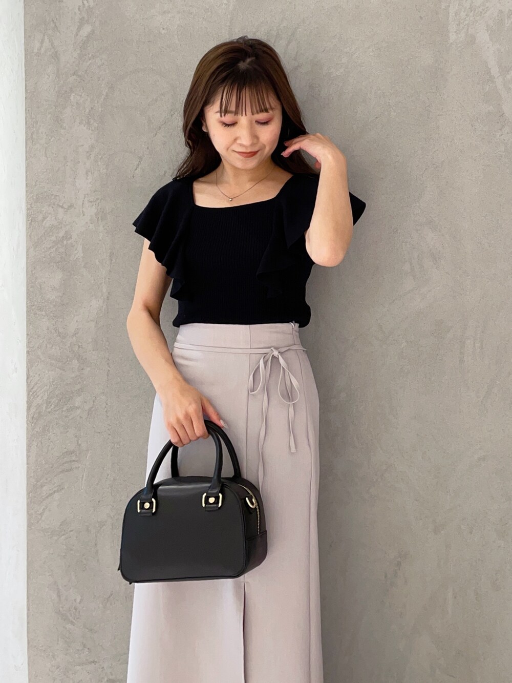 ブラック系のボストンバッグ、ブラック系のニット/セーター、ブラック系のサンダルを着用したレディースの春コーディネートの3枚目の写真