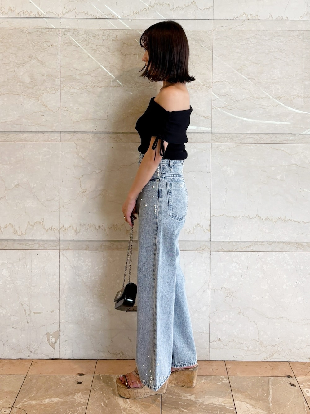 ブラック系のボディバッグ/ウエストポーチ、ブラック系のニット/セーター、ブルー系のデニムパンツを着用したレディースの夏コーディネートの7枚目の写真