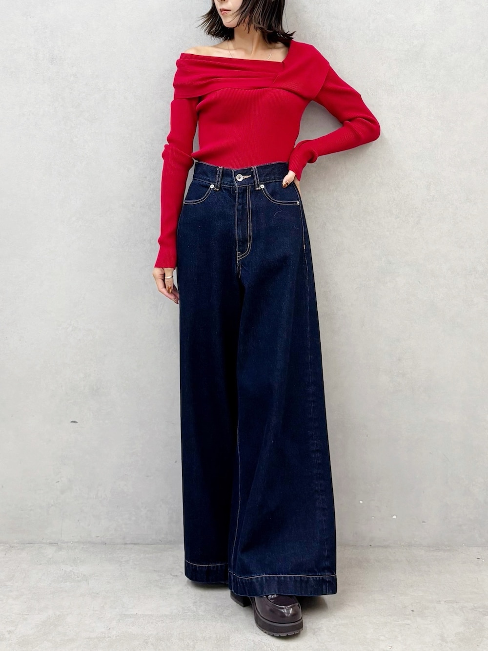 レッド系のニット/セーター、ブルー系のデニムパンツ、ブラウン系のブーツを着用したレディースの秋コーディネートの8枚目の写真