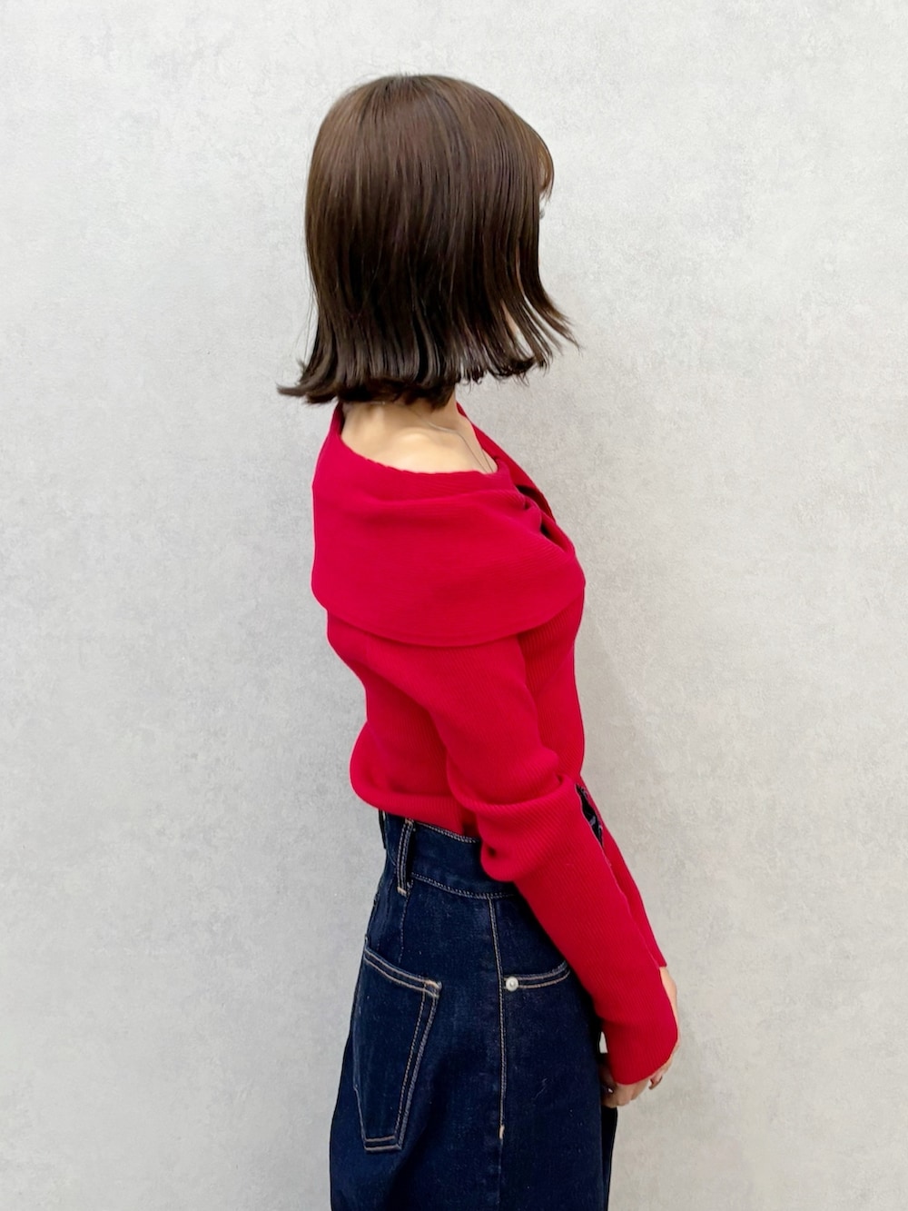 レッド系のニット/セーター、ブルー系のデニムパンツ、ブラウン系のブーツを着用したレディースの秋コーディネートの3枚目の写真