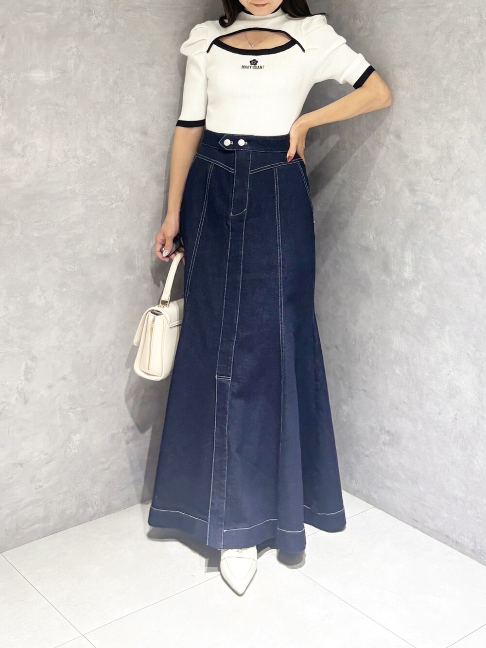 ブルー系のスカート、ホワイト系のパンプス、ホワイト系のハンドバッグを着用したレディースの春コーディネートの6枚目の写真